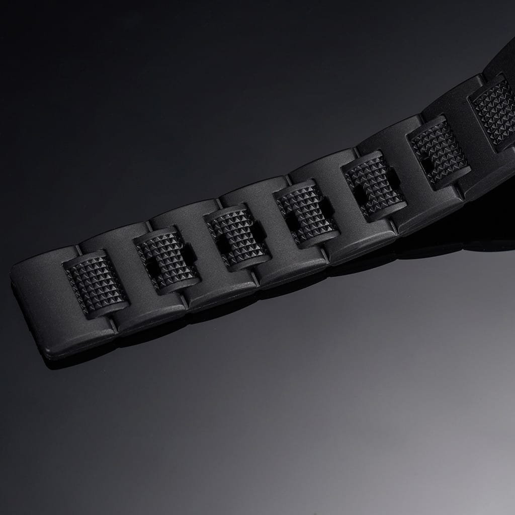 Black rubber watch strap close-up with textured segments and raised lug pattern
