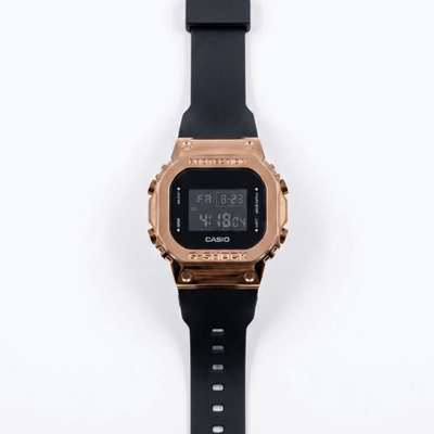 Casio G-Shock digital watch with rose-gold metal bezel and black silicone strap