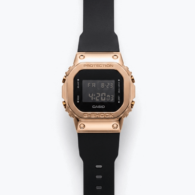 Casio G-Shock digital watch with rose-gold bezel, black strap, and LCD display