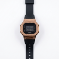 Digital watch with rose gold bezel, black silicone strap, and LCD time display