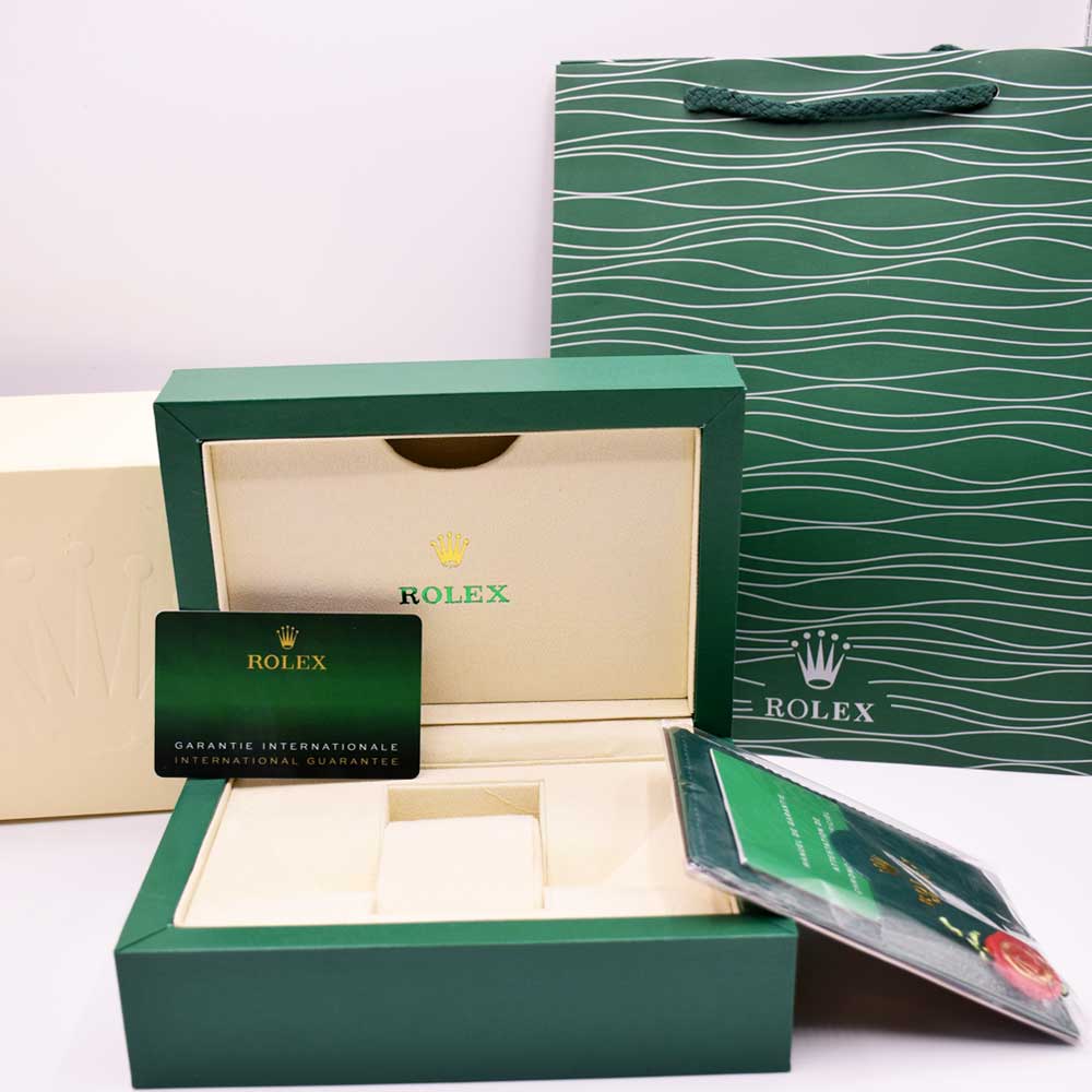 Rolex watch box open with beige tray, guarantee card, and green booklet