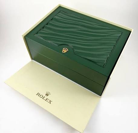 Rolex watch box open with green outer cover and beige bottom paper sleeve